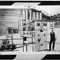 Power house at dam #5, circa 1904. INTERIOR OF ORIGINAL POWER HOUSE, SHOWING M.P.C. SUPERINTENDENT H. B. SHOEMAKER BESIDE SWITCH. AT LEFT IS A REPLOGLE RELAY WATER WHEEL GOVERNOR HAER WVA,2-HEDVI.V,1-4.tif