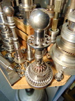 An AiResearch small gas turbine fuel control surrounded by whimsical gas turbine fuel control parts and tooling.